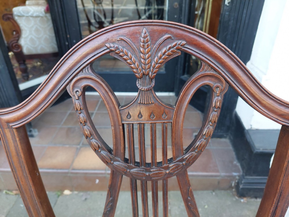 A set of six late nineteenth-century mahogany dining chairs featuring shield-shaped backs with carved lyre motifs and pale green upholstered seats. View V