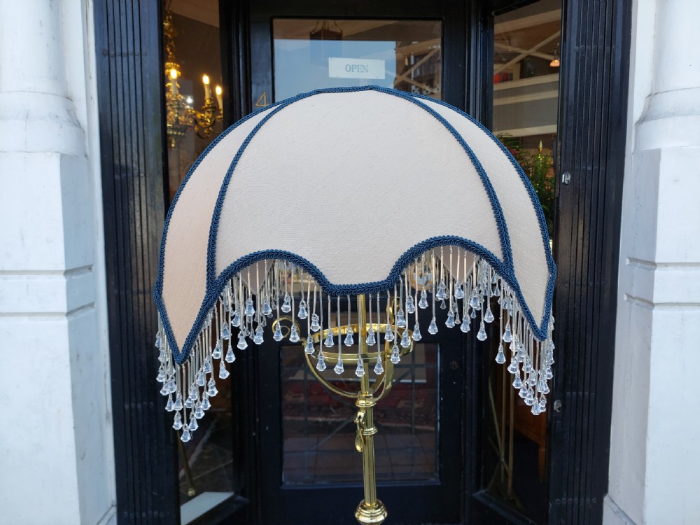 An Arts and Crafts brass standard floor lamp featuring a scrollwork tripod base, floral copper accents, and a fringe-trimmed domed shade. View V