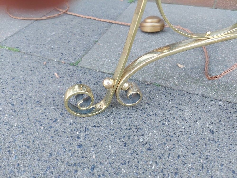 An Arts and Crafts brass standard floor lamp featuring a scrollwork tripod base, floral copper accents, and a fringe-trimmed domed shade. View VI