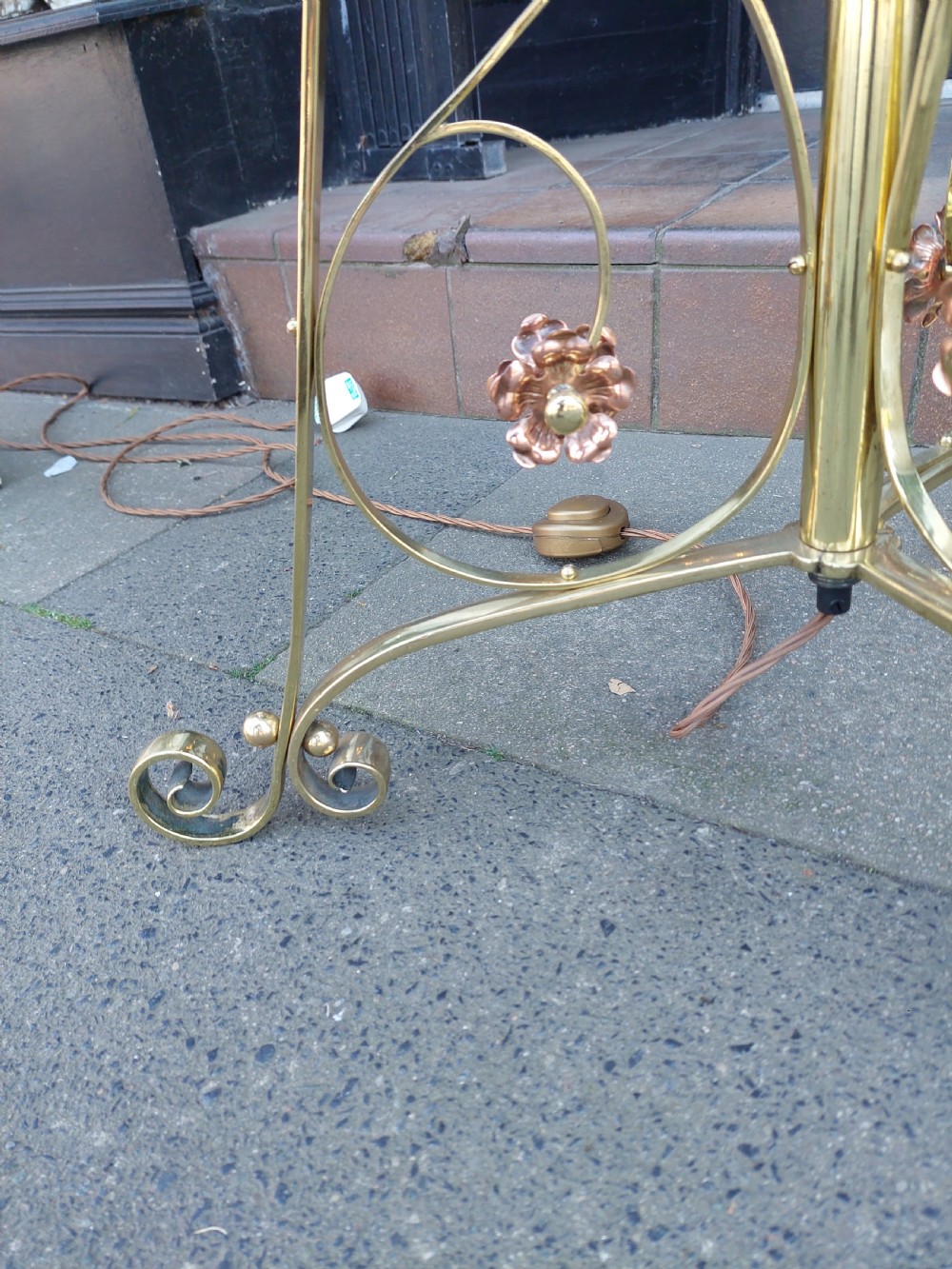 An Arts and Crafts brass standard floor lamp featuring a scrollwork tripod base, floral copper accents, and a fringe-trimmed domed shade. View VII