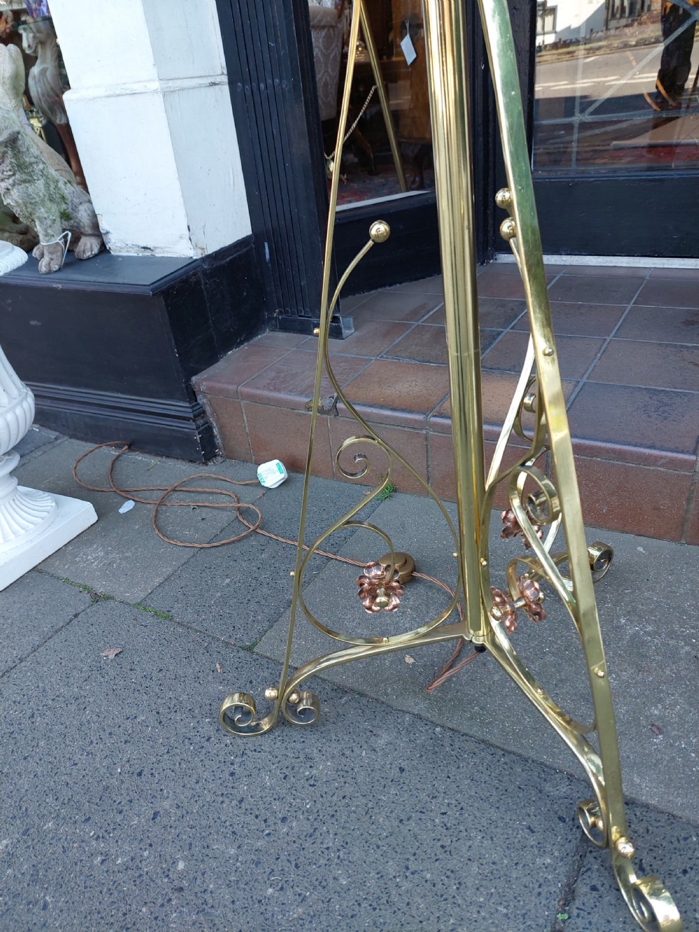 An Arts and Crafts brass standard floor lamp featuring a scrollwork tripod base, floral copper accents, and a fringe-trimmed domed shade. View VIII