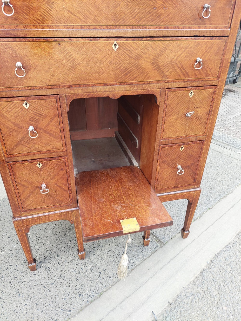 A late 19th-century George II style mahogany kneehole desk featuring herringbone inlay, brass drop handles, and a central recessed cupboard. View II