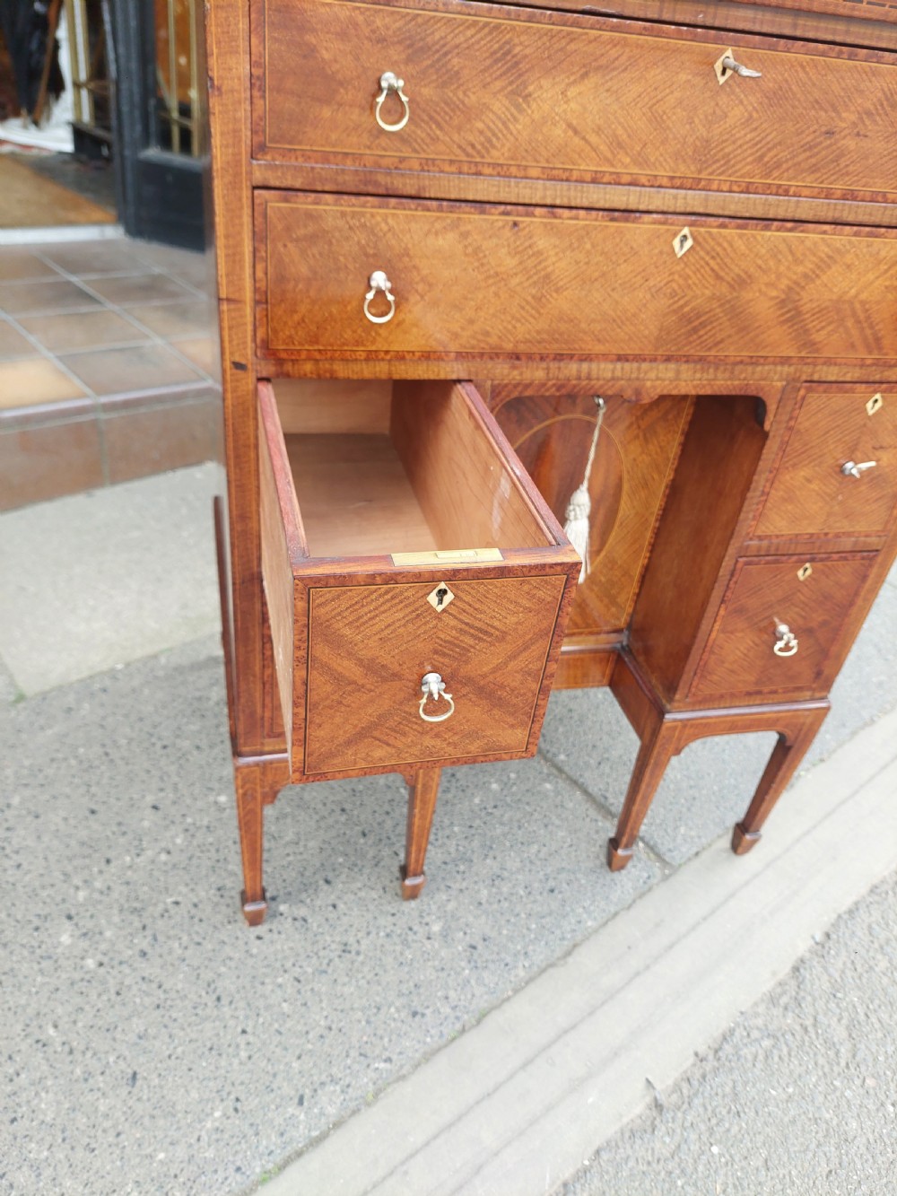 A late 19th-century George II style mahogany kneehole desk featuring herringbone inlay, brass drop handles, and a central recessed cupboard. View IV