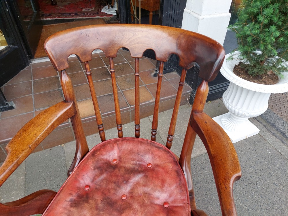 An early 19th-century mahogany desk chair featuring a spindle back, curved armrests, a red leather seat cushion, turned front legs, and brass castors. View IV