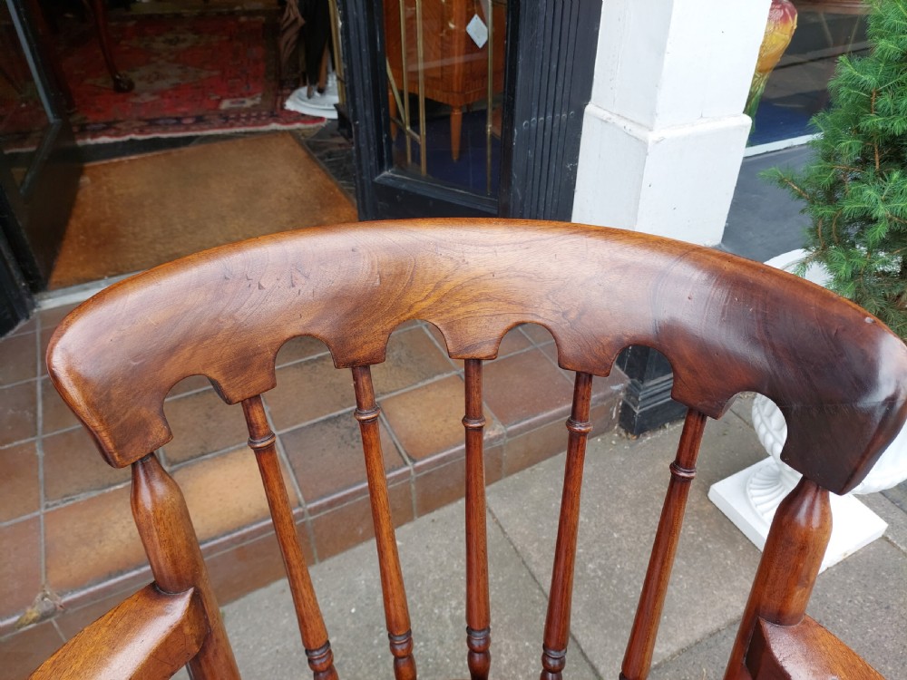 An early 19th-century mahogany desk chair featuring a spindle back, curved armrests, a red leather seat cushion, turned front legs, and brass castors. View V