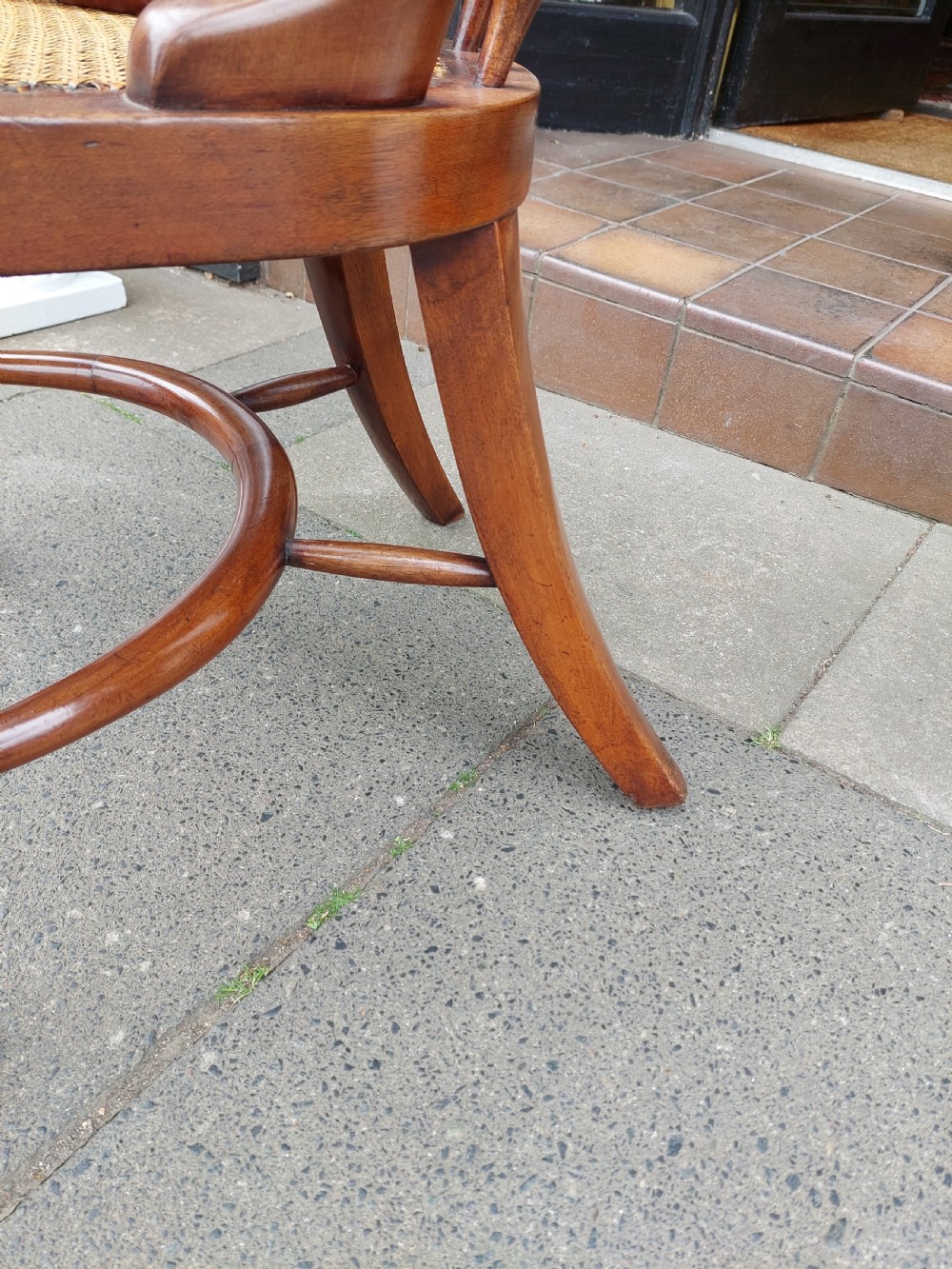 An early 19th-century mahogany desk chair featuring a spindle back, curved armrests, a red leather seat cushion, turned front legs, and brass castors. View X