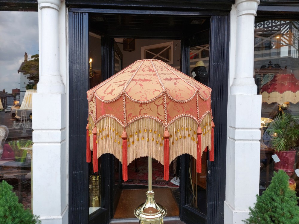 A late nineteenth-century brass standard floor lamp featuring a polished metal column with decorative swags and an ornate pink fabric shade with tassel fringe. View II