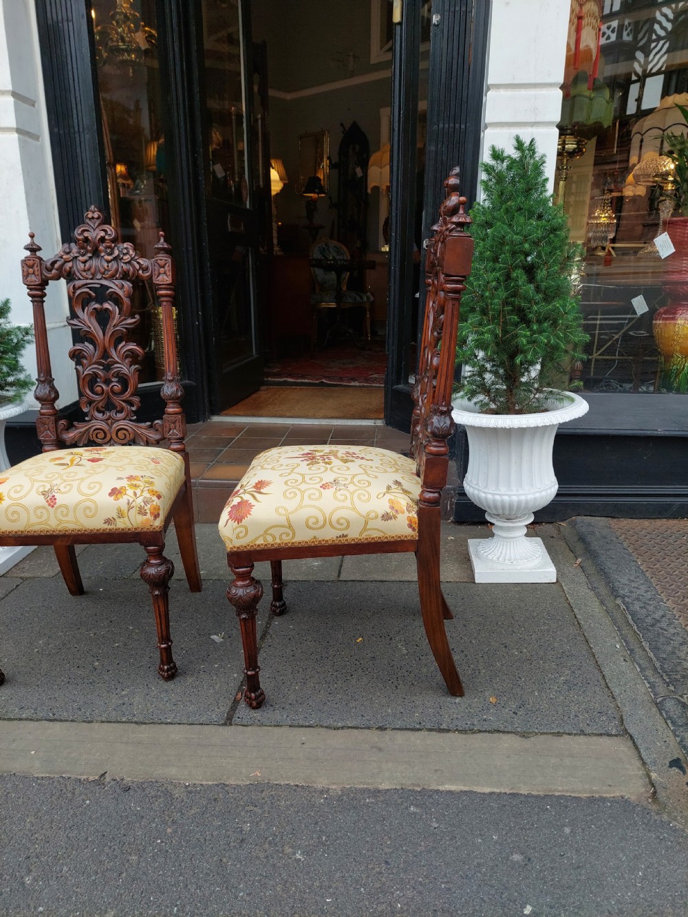 A pair of nineteenth-century carved walnut side chairs featuring openwork scrollwork backrests, turned legs, and cream floral pattern upholstery. View II