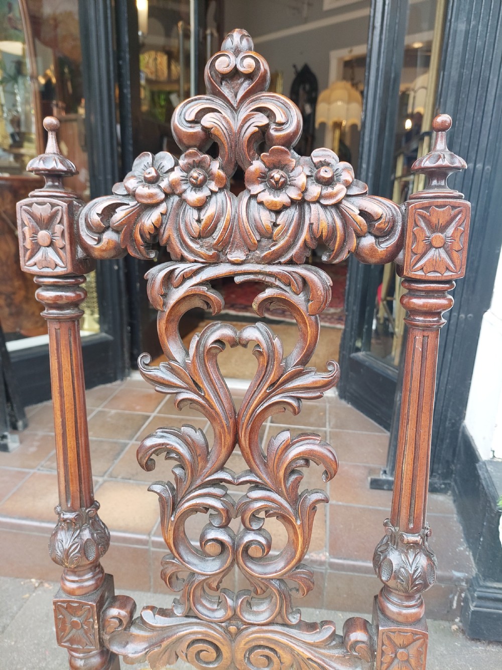 A pair of nineteenth-century carved walnut side chairs featuring openwork scrollwork backrests, turned legs, and cream floral pattern upholstery. View V