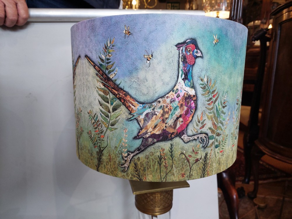 A pair of early 20th-century table lamps with square brass bases, twisted clear glass columns, and drum lampshades featuring countryside wildlife illustrations. View VI