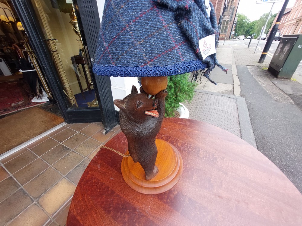 An early twentieth-century carved lindenwood Black Forest bear table lamp topped with a blue tartan fabric lampshade. View II
