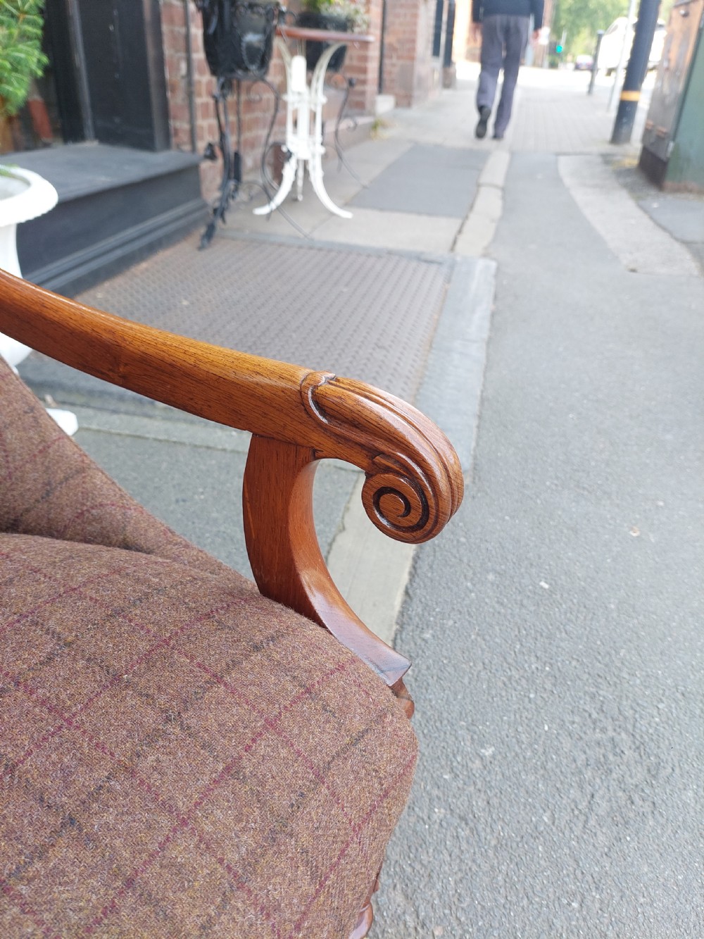 An early 19th-century rosewood armchair with brown button-back upholstery, carved scroll arms, turned front legs, and brass castors. View II