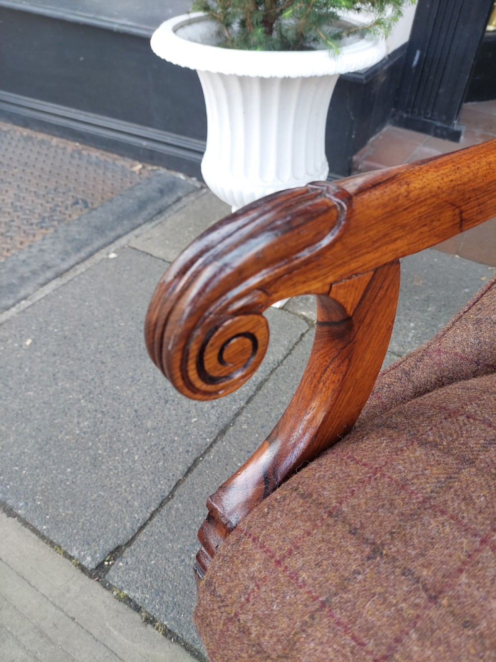 An early 19th-century rosewood armchair with brown button-back upholstery, carved scroll arms, turned front legs, and brass castors. View III
