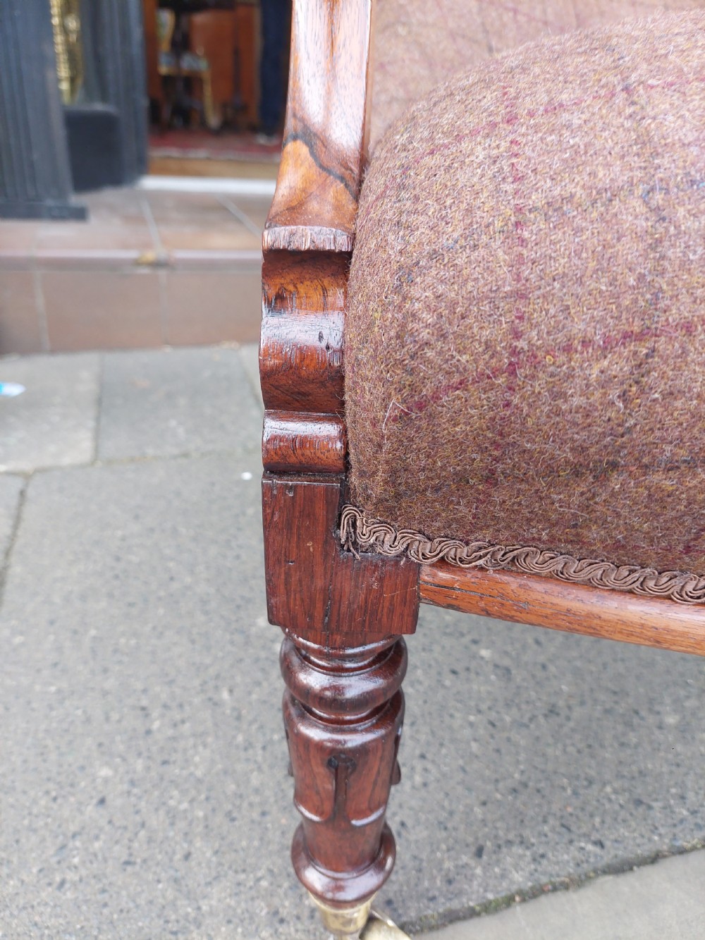 An early 19th-century rosewood armchair with brown button-back upholstery, carved scroll arms, turned front legs, and brass castors. View VIII