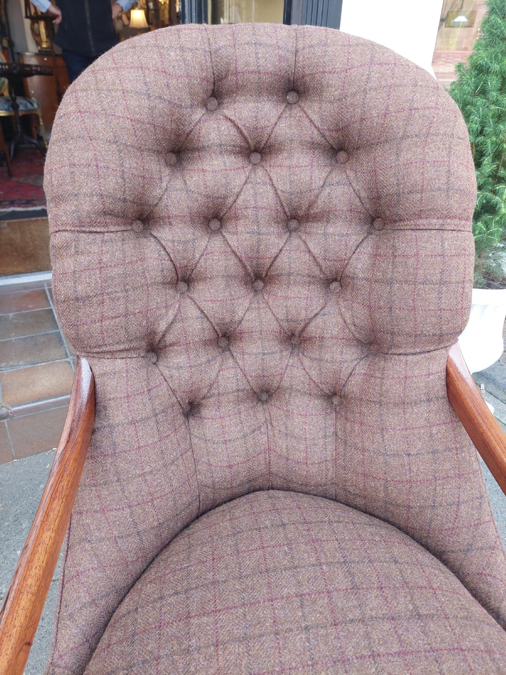 An early 19th-century rosewood armchair with brown button-back upholstery, carved scroll arms, turned front legs, and brass castors. View IX