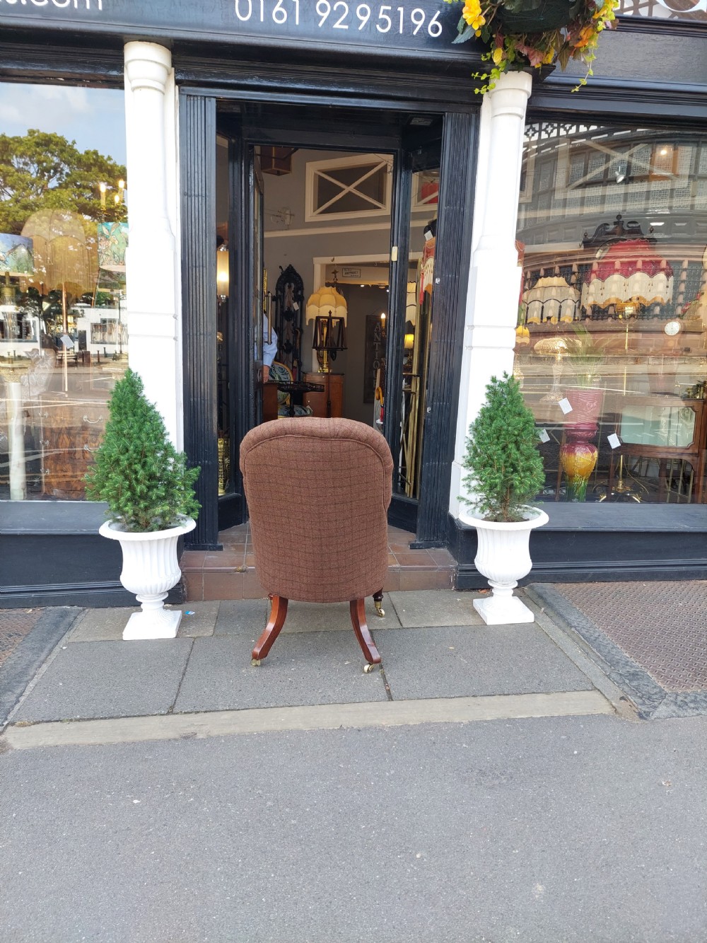 An early 19th-century rosewood armchair with brown button-back upholstery, carved scroll arms, turned front legs, and brass castors. View XI