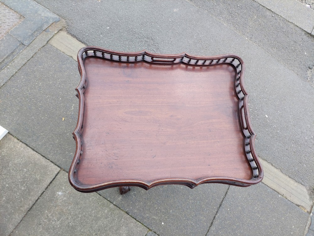 A George III mahogany snap top table featuring a rectangular top with a spindle gallery rim, set on a turned stem with carved tripod legs. View III
