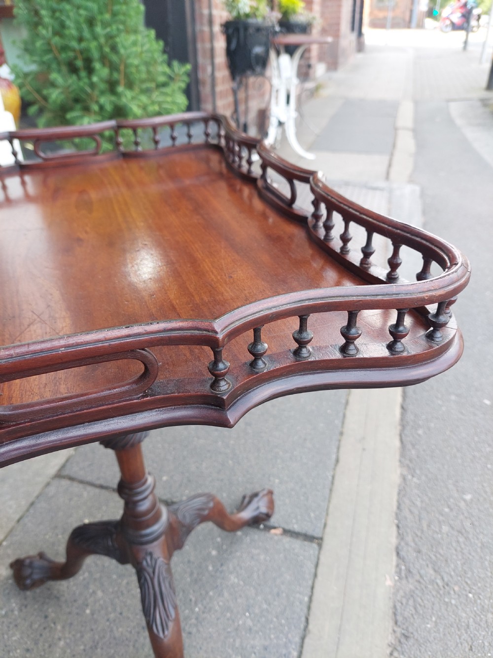 A George III mahogany snap top table featuring a rectangular top with a spindle gallery rim, set on a turned stem with carved tripod legs. View IV