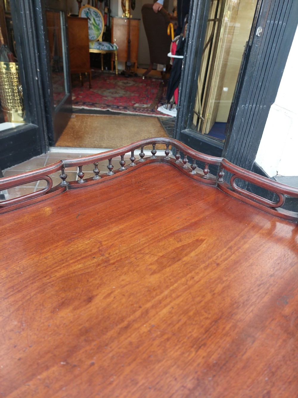 A George III mahogany snap top table featuring a rectangular top with a spindle gallery rim, set on a turned stem with carved tripod legs. View V