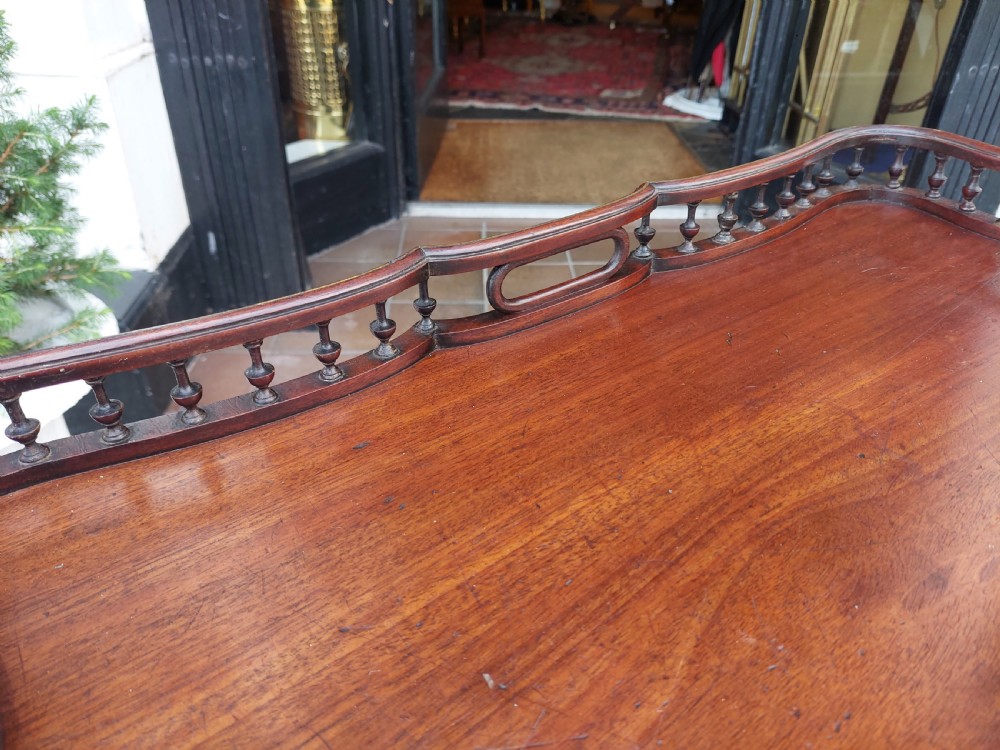 A George III mahogany snap top table featuring a rectangular top with a spindle gallery rim, set on a turned stem with carved tripod legs. View VI
