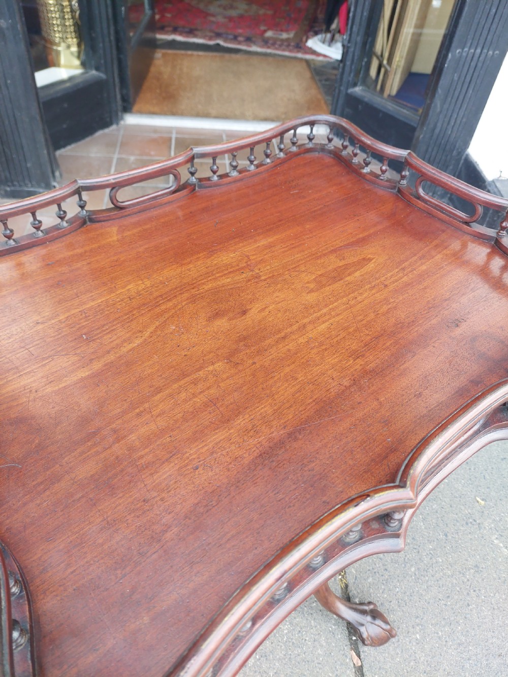 A George III mahogany snap top table featuring a rectangular top with a spindle gallery rim, set on a turned stem with carved tripod legs. View VII