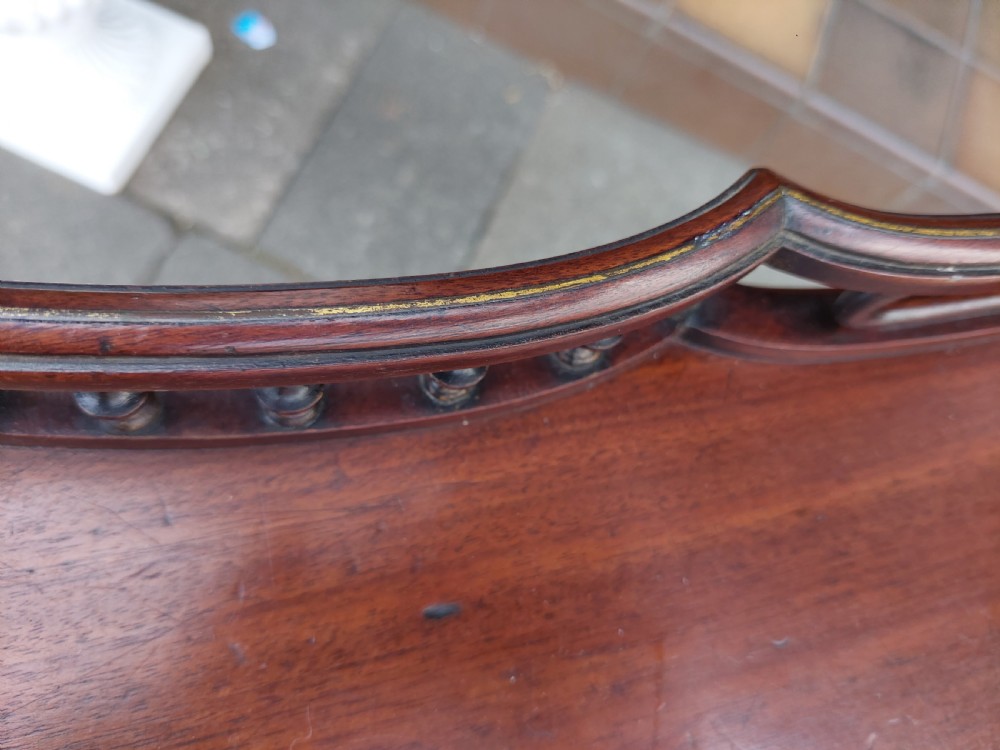 A George III mahogany snap top table featuring a rectangular top with a spindle gallery rim, set on a turned stem with carved tripod legs. View VIII