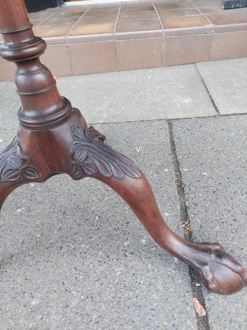 A George III mahogany snap top table featuring a rectangular top with a spindle gallery rim, set on a turned stem with carved tripod legs. View X