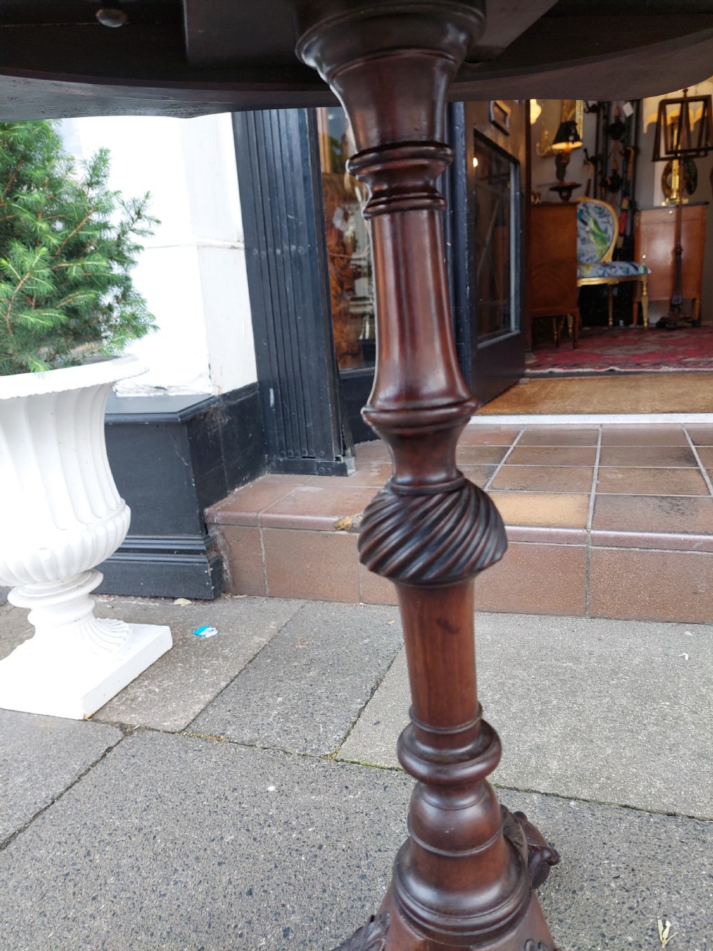 A George III mahogany snap top table featuring a rectangular top with a spindle gallery rim, set on a turned stem with carved tripod legs. View XI