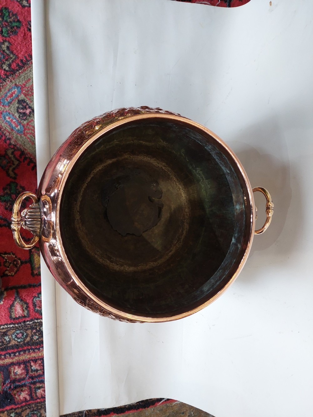 A bulbous Victorian polished copper vessel featuring embossed floral scrollwork, lower gadrooned fluting, two side loop handles, and a circular stepped pedestal base. View III
