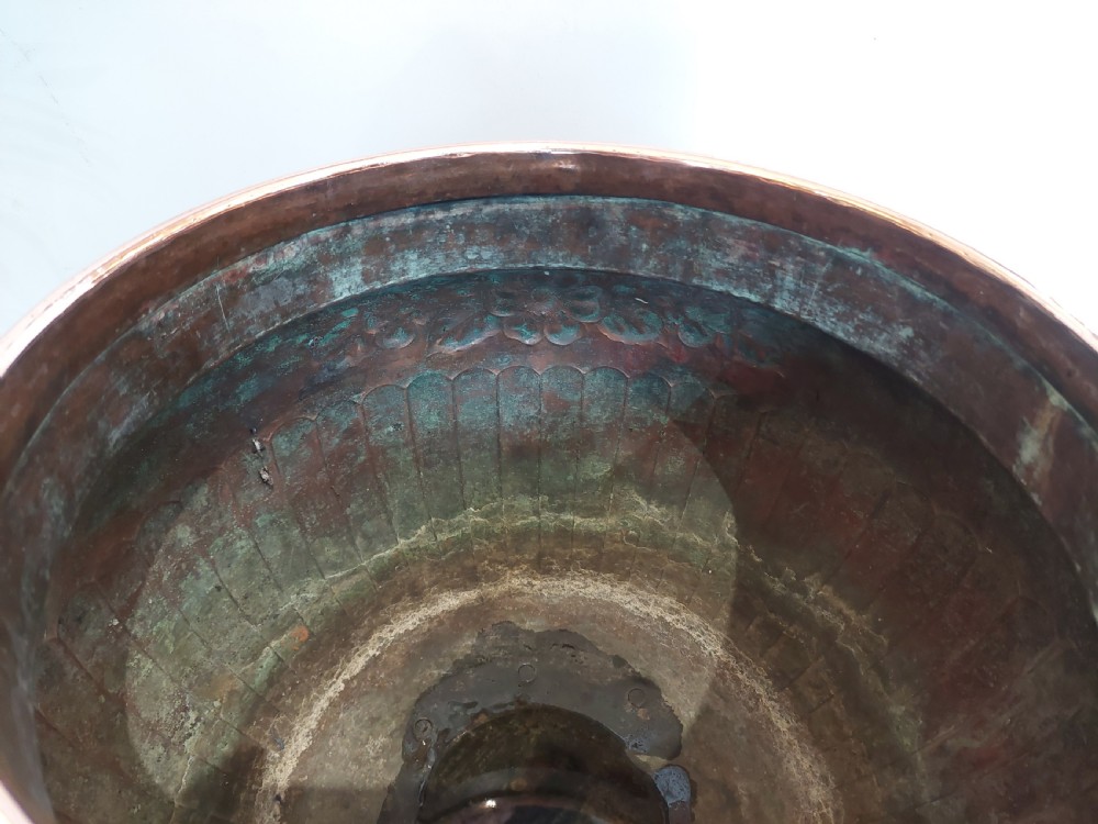 A bulbous Victorian polished copper vessel featuring embossed floral scrollwork, lower gadrooned fluting, two side loop handles, and a circular stepped pedestal base. View VIII