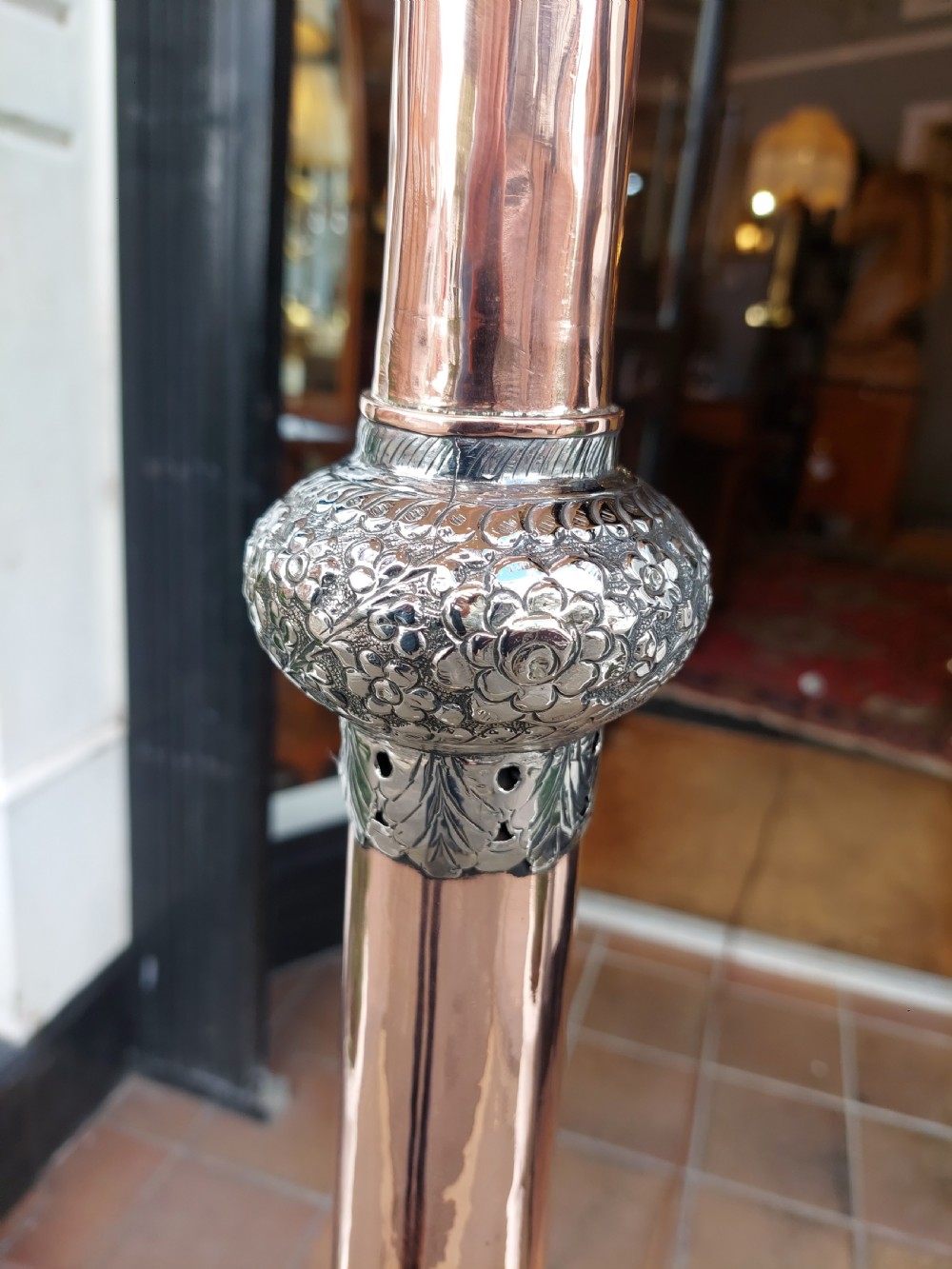 A tall floor lamp made from a tapered copper and white metal horn stem topped with a cream fabric dome shade featuring long tassel fringe. View VI