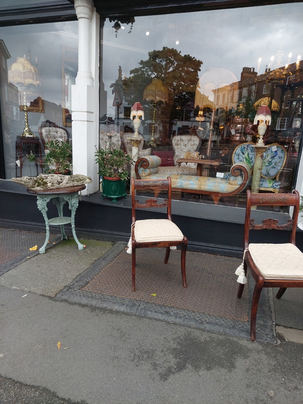 A set of six English Regency dining chairs featuring faux rosewood graining, brass inlay on the top rails, carved central splats, sabre front legs, and cream upholstered cushions. View IV