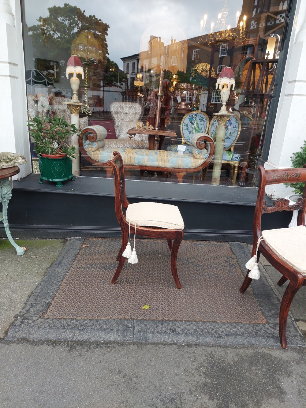 A set of six English Regency dining chairs featuring faux rosewood graining, brass inlay on the top rails, carved central splats, sabre front legs, and cream upholstered cushions. View V