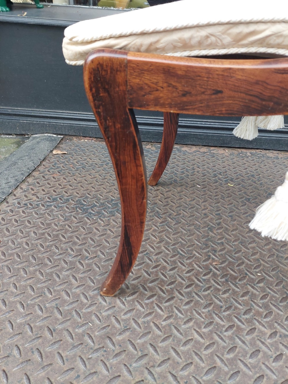 A set of six English Regency dining chairs featuring faux rosewood graining, brass inlay on the top rails, carved central splats, sabre front legs, and cream upholstered cushions. View VII