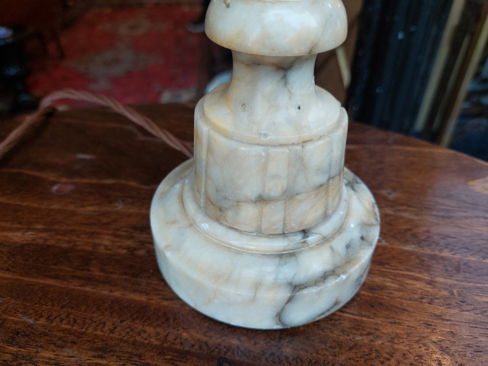 A pair of carved white alabaster urn-form table lamps featuring pink velvet shades trimmed with white tassel fringe. View VI