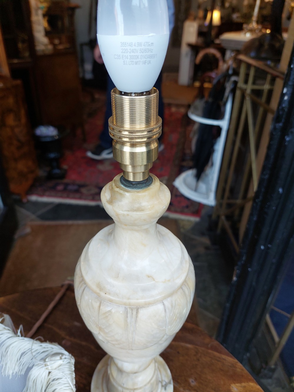 A pair of carved white alabaster urn-form table lamps featuring pink velvet shades trimmed with white tassel fringe. View VII