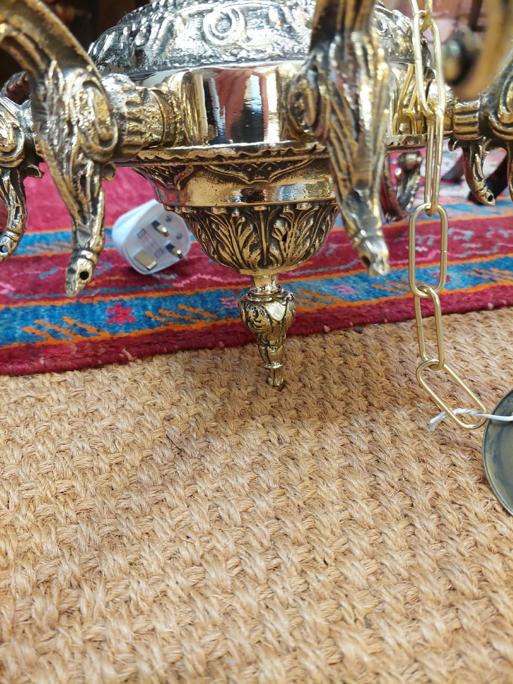 An eight-arm cast brass chandelier featuring detailed acanthus leaf mounts, scrollwork arms, and white candle-effect lamp holders. View VIII