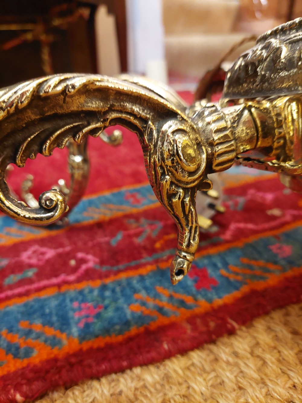 An eight-arm cast brass chandelier featuring detailed acanthus leaf mounts, scrollwork arms, and white candle-effect lamp holders. View IX