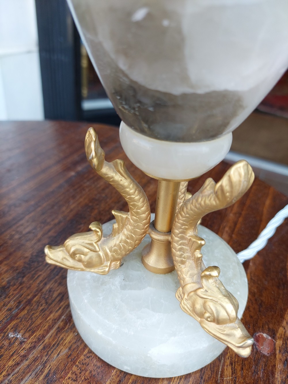 A pair of white veined onyx table lamps featuring gilt metal dolphin feet and flared white fabric shades with fringe. View IV