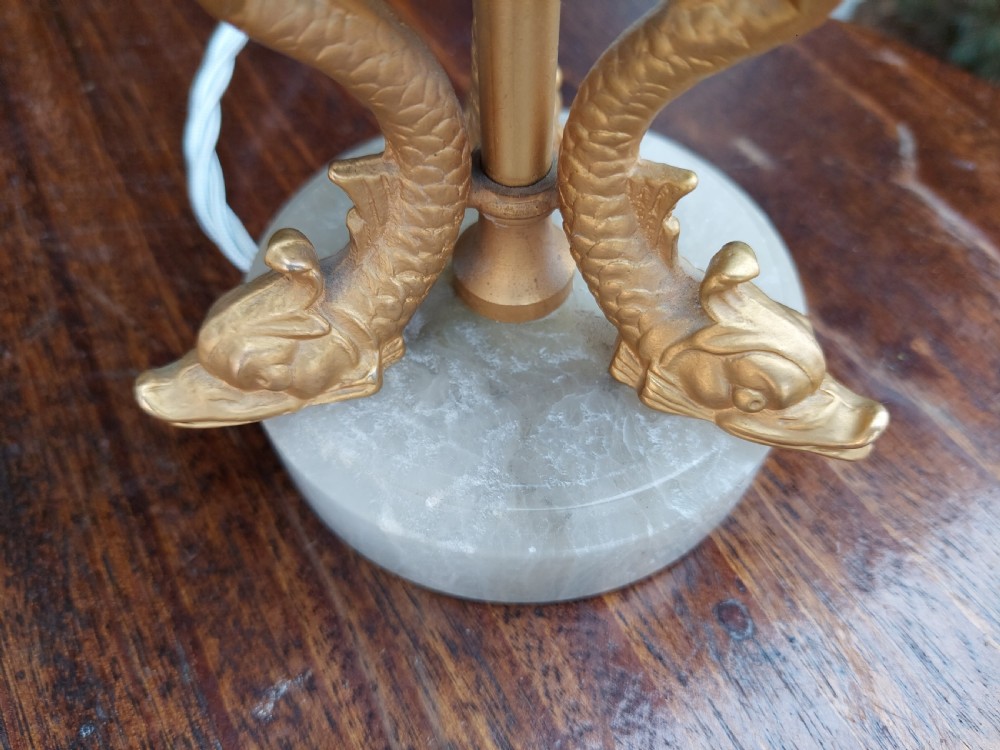 A pair of white veined onyx table lamps featuring gilt metal dolphin feet and flared white fabric shades with fringe. View IX