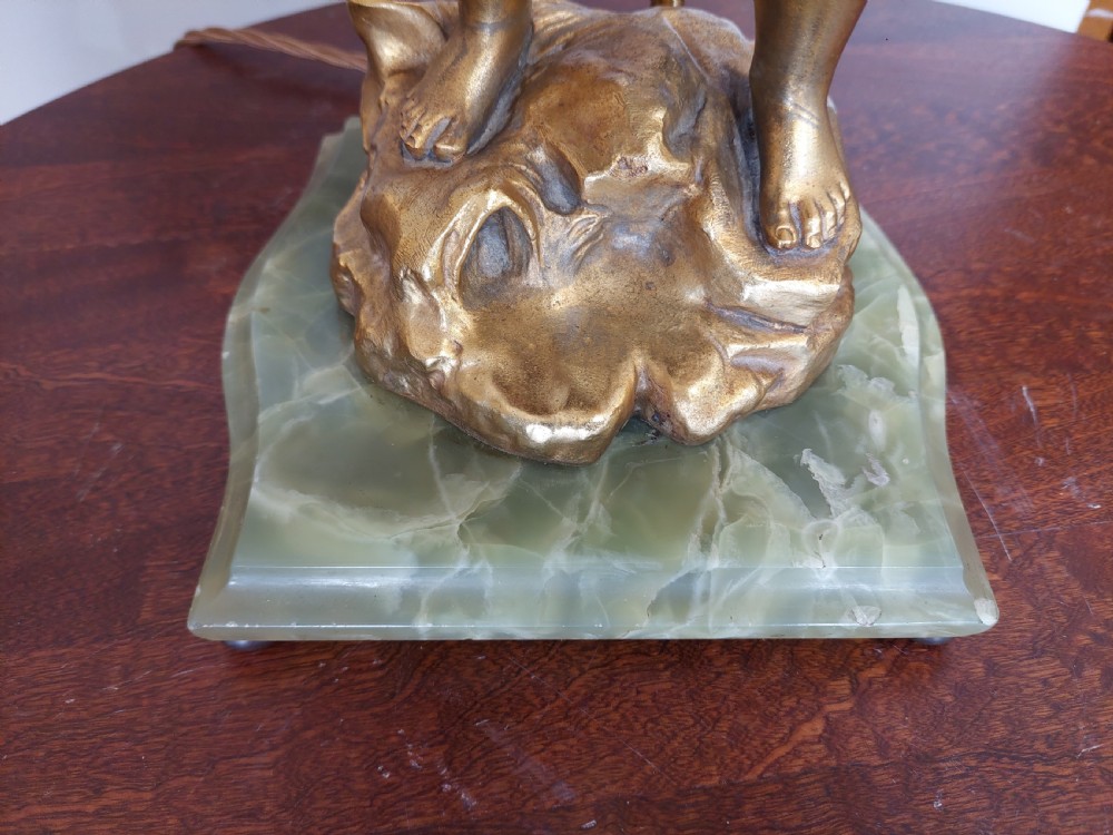 A 19th-century French gilt bronze table lamp featuring a sculpted cherub carrying a vessel, mounted on a marble plinth and topped with a red fringed dome shade. View II