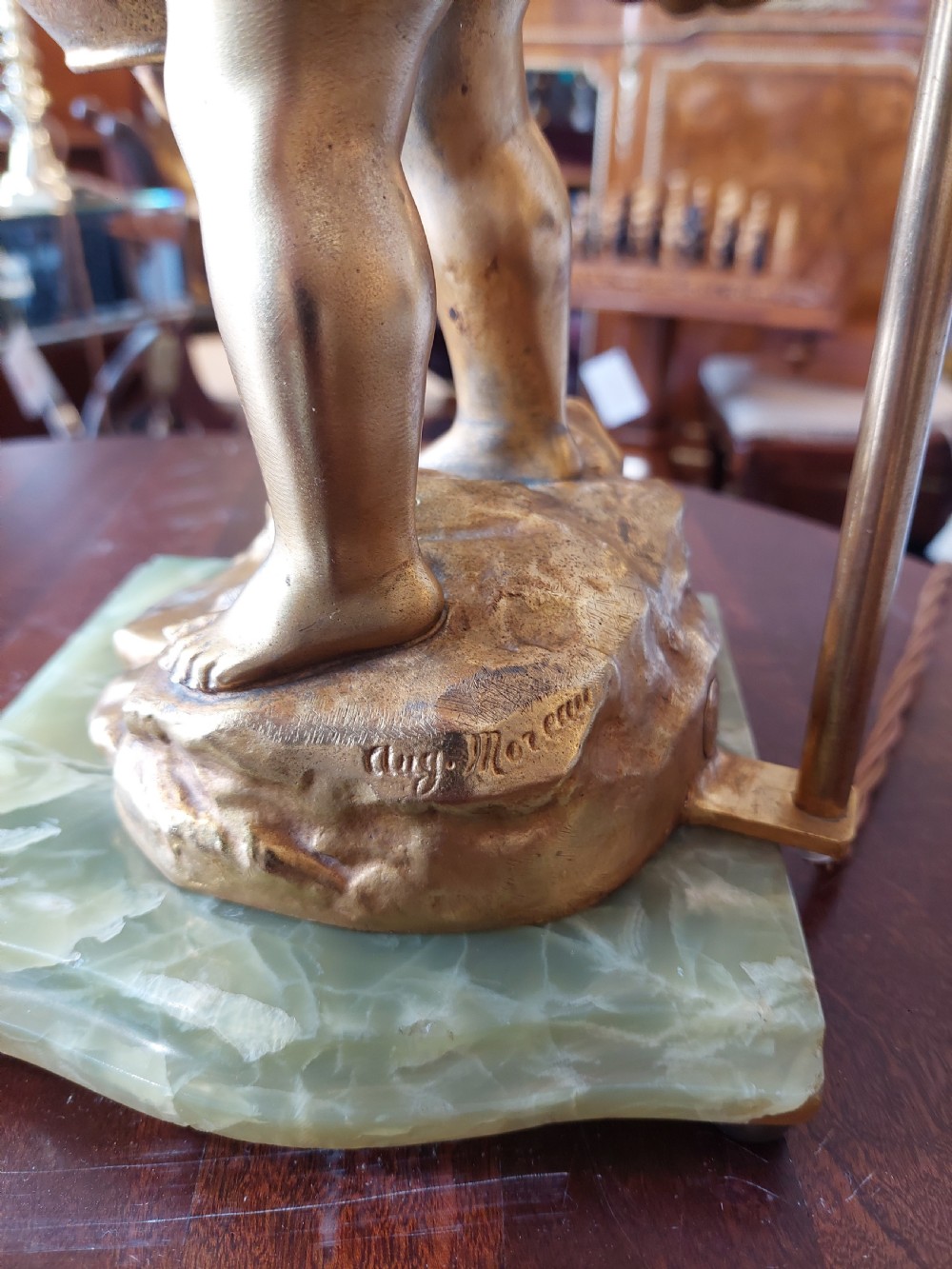 A 19th-century French gilt bronze table lamp featuring a sculpted cherub carrying a vessel, mounted on a marble plinth and topped with a red fringed dome shade. View III