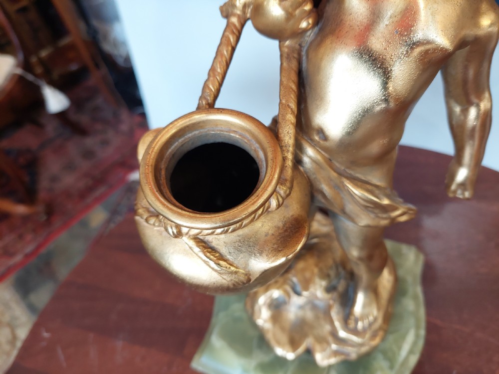 A 19th-century French gilt bronze table lamp featuring a sculpted cherub carrying a vessel, mounted on a marble plinth and topped with a red fringed dome shade. View IV