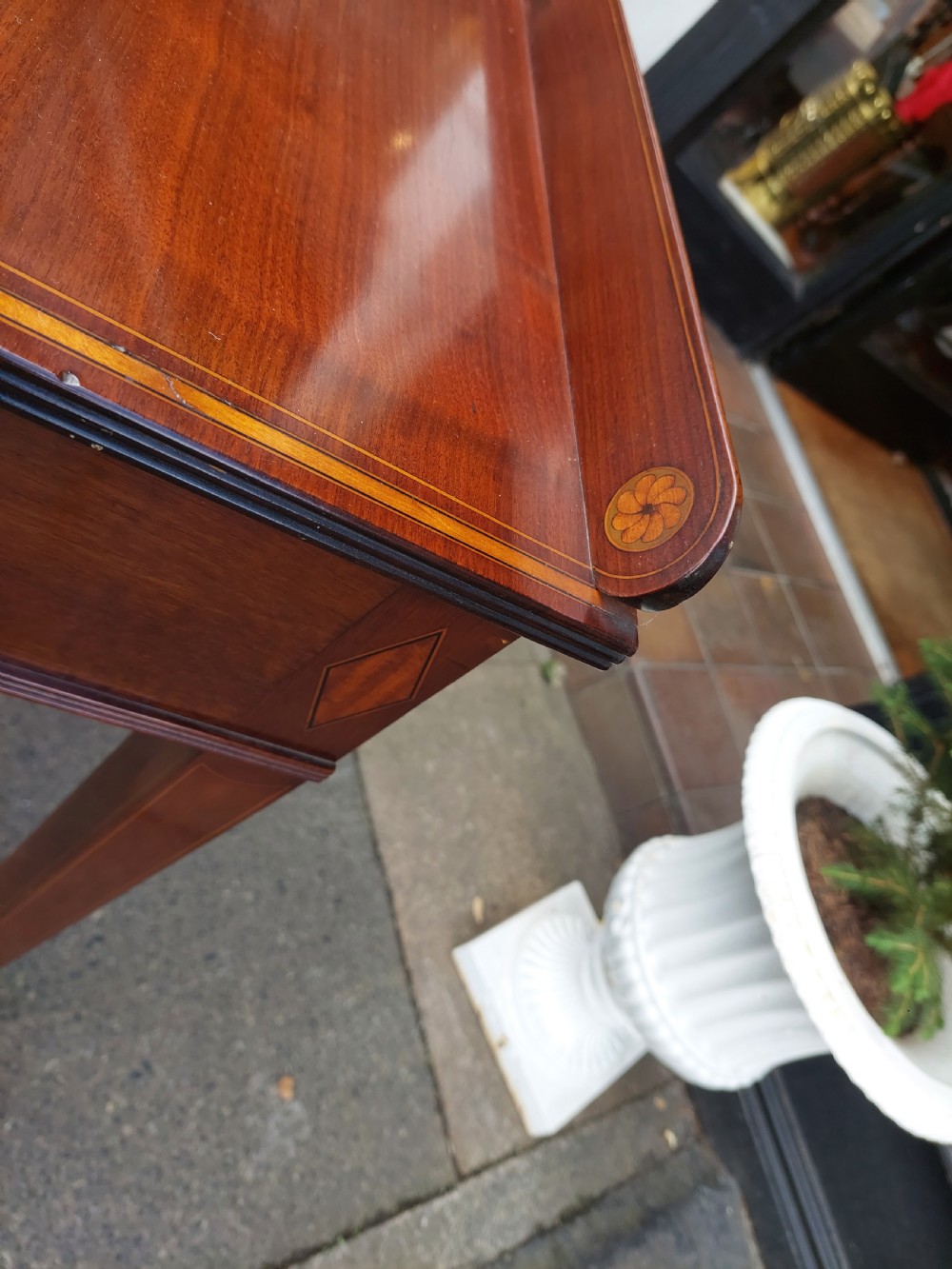 An Edwardian mahogany hall table featuring two inlaid drawers with brass ring handles, tapered square legs with brass castors, and a low rear gallery. View VI