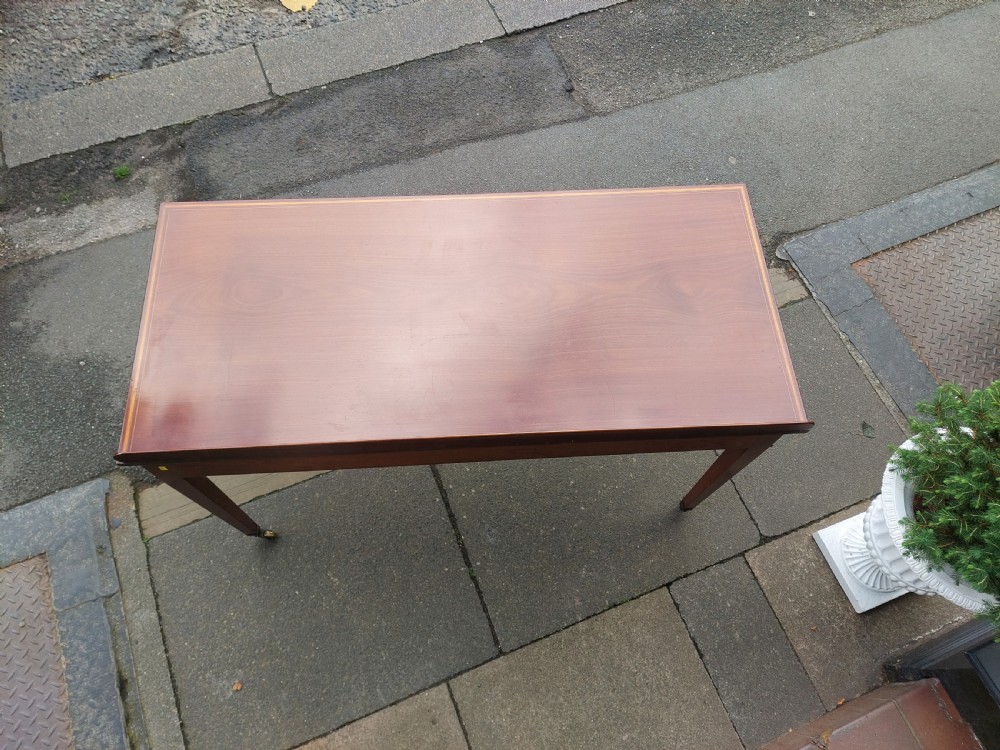 An Edwardian mahogany hall table featuring two inlaid drawers with brass ring handles, tapered square legs with brass castors, and a low rear gallery. View VIII