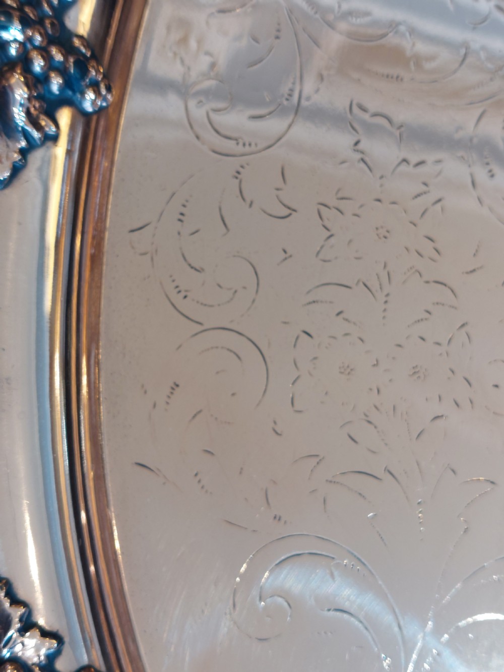 A 19th-century oval copper serving tray featuring detailed scrollwork engraving on the surface, a relief grapevine border, and two cast handles. View IV