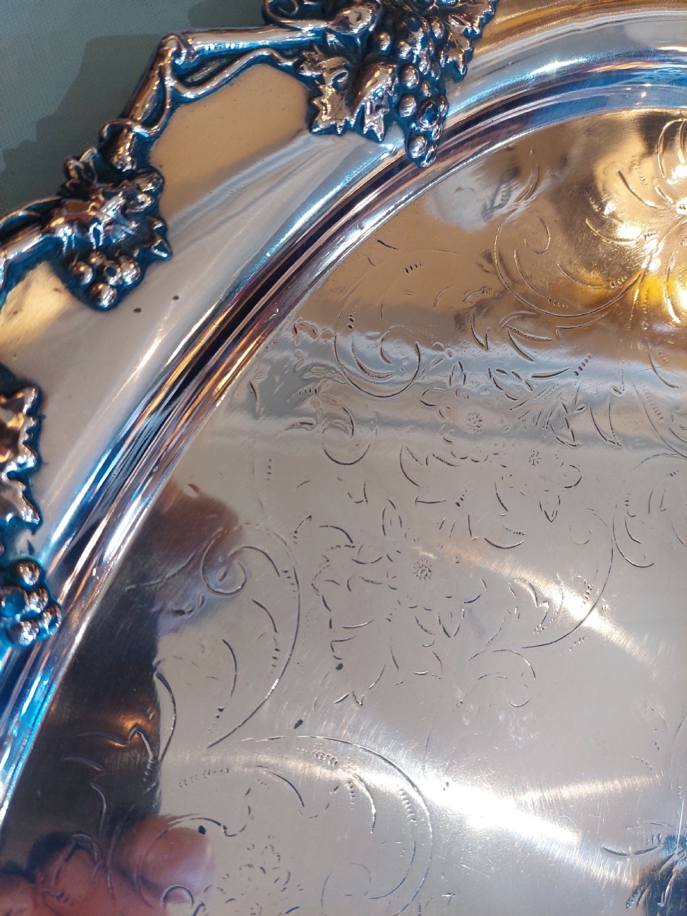 A 19th-century oval copper serving tray featuring detailed scrollwork engraving on the surface, a relief grapevine border, and two cast handles. View VI