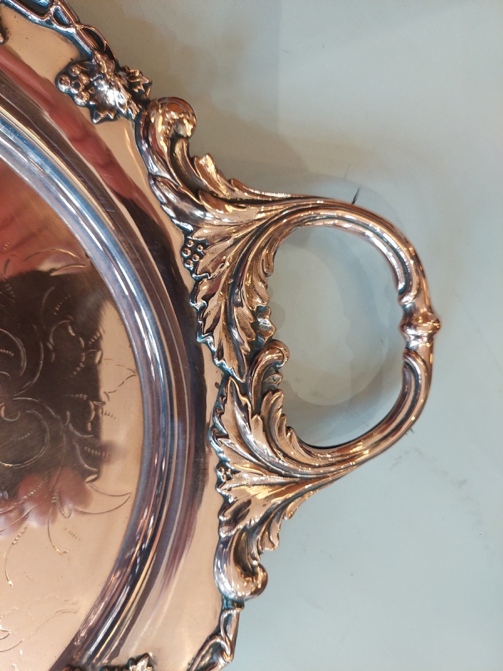 A 19th-century oval copper serving tray featuring detailed scrollwork engraving on the surface, a relief grapevine border, and two cast handles. View VII