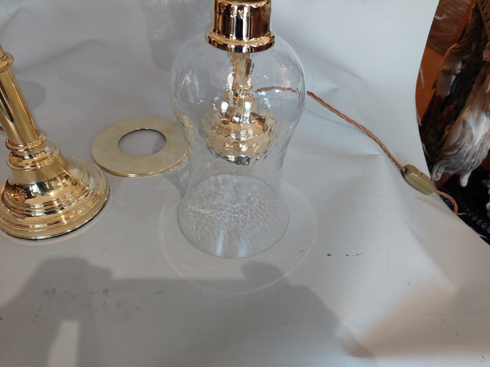 A pair of turned brass table lamps with stepped circular bases, cylindrical stems, and clear flared glass storm shades. View VI