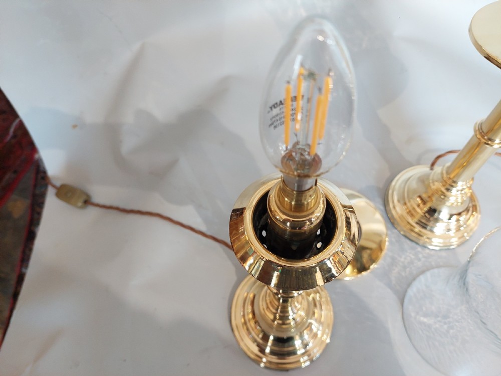 A pair of turned brass table lamps with stepped circular bases, cylindrical stems, and clear flared glass storm shades. View IX